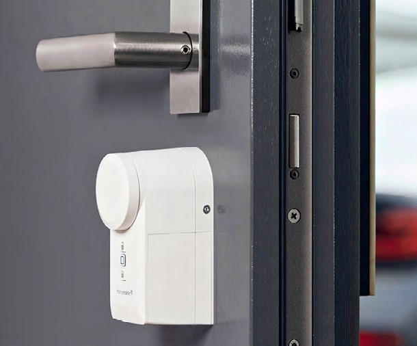 Homematic IP Türschlossantrieb HmIP-DLD an einer weißen Tür.